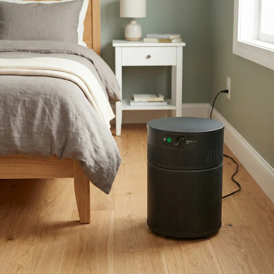 Black Airpura r400 air purifier on a wooden floor in a bedroom