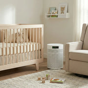 Nursery room with crib, white Airpura R400 air purifier, and armchair